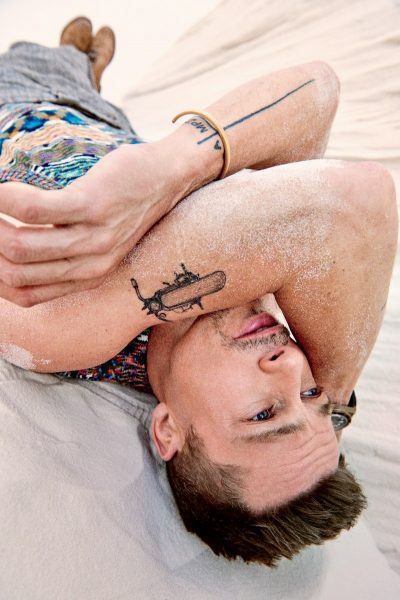 brad pitt laying in sand wrapped arms