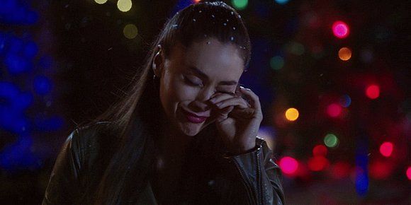 Lindsey Morgan wiping tears from eyes in front of Christmas tree.