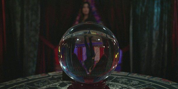 Blurred reflection of Cassie in crystal ball on palm readers table 2.14.